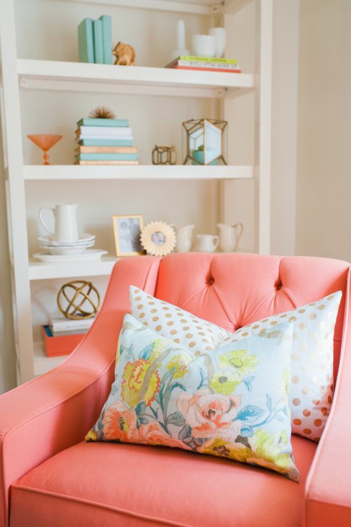 fauteuil rose saumon, étagère blanche, coussins déco motifs floraux, accessoires déco