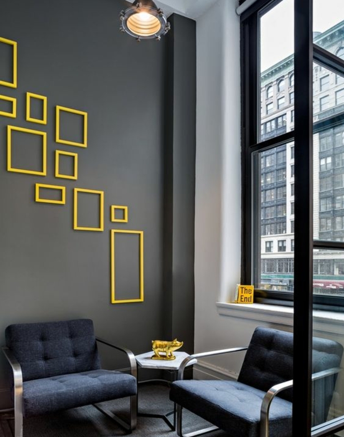 mur de cadres vides jaunes, format divers, couleur mur gris anthracite, fauteuil bleu foncé, decoration cochon doré, suspension industrielle