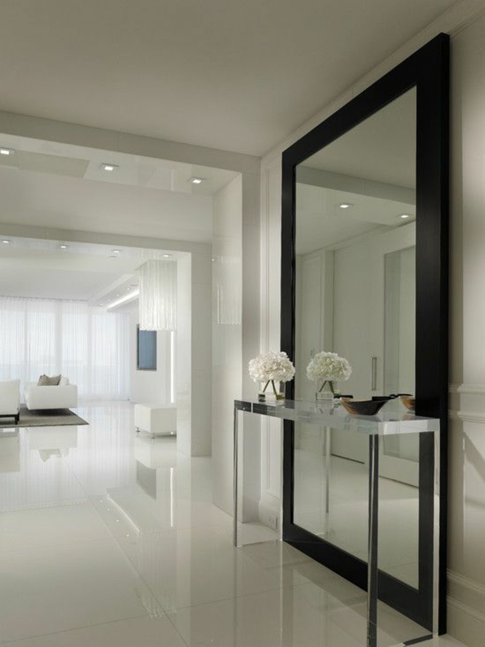 decoration hall de maison au sol au carrelage brillant et au grand miroir au cadre noir et une table haute en métal blanc 