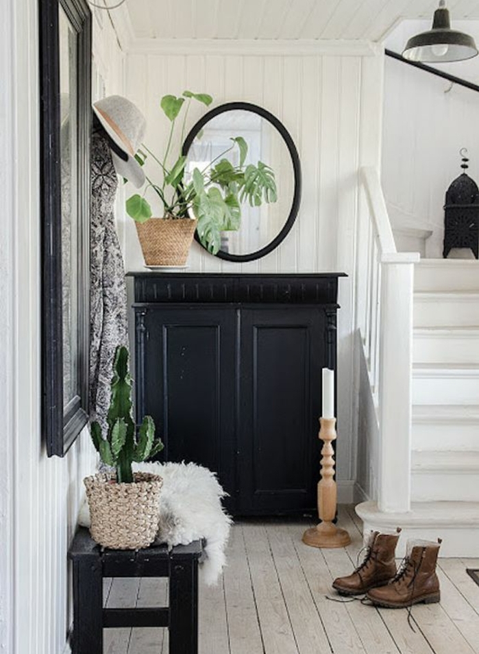 exemple de hall entrée maison, meuble chaussures noir, parquet clair, miroir ovale et grand miroir rectangulaire, plante verte, lambris blanc