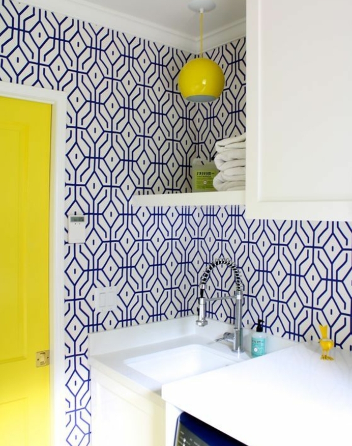 deco bleu et jaune dans la cuisine, mur habillé de papier peint blanc à motifs géométriques bleus, porte jaune, façade cuisine blanche