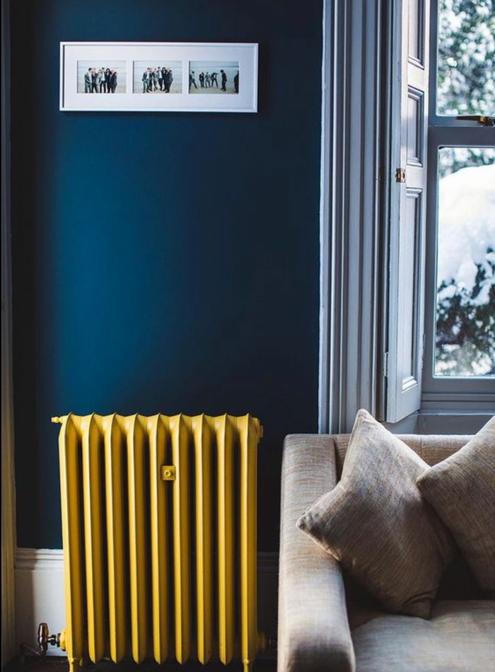 deco bleu et jaune, un radiateur repeint en jaune pastel, canapé gris et mur couleur bleu foncé, decoration murale de photos