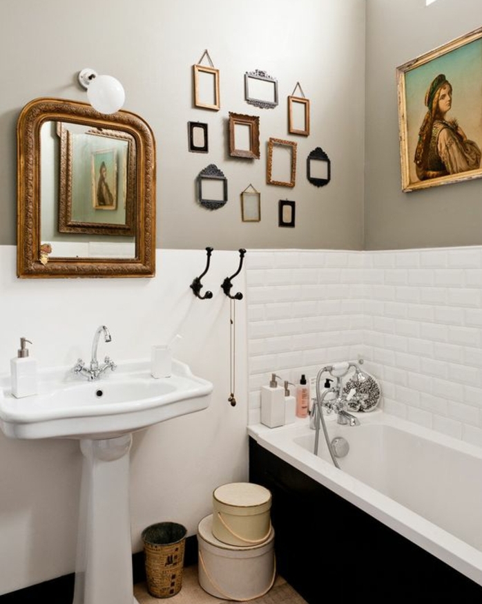 salle de bain en blanc et gris, carrelage blanc, lavabo colonne, miroir vintage, baignoire encastrée, deco cadre vide, plusieurs petits cadres photo retro