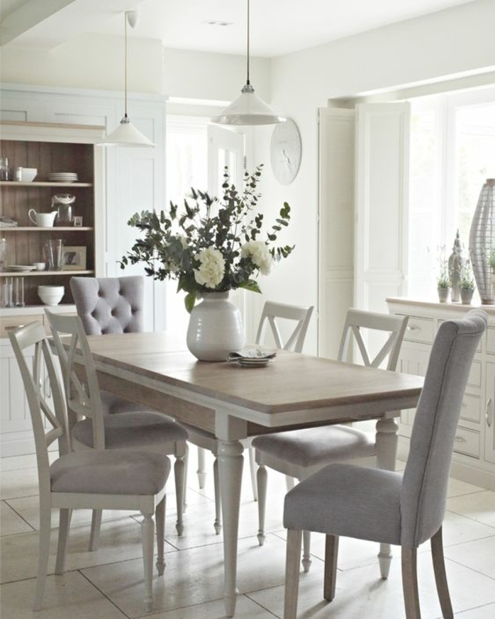 deco campagne chic dans la salle à manger, table en bois, chaises en bois blanches avec revêtement gris, vase de fleurs, vaisselier blanc, suspensions
