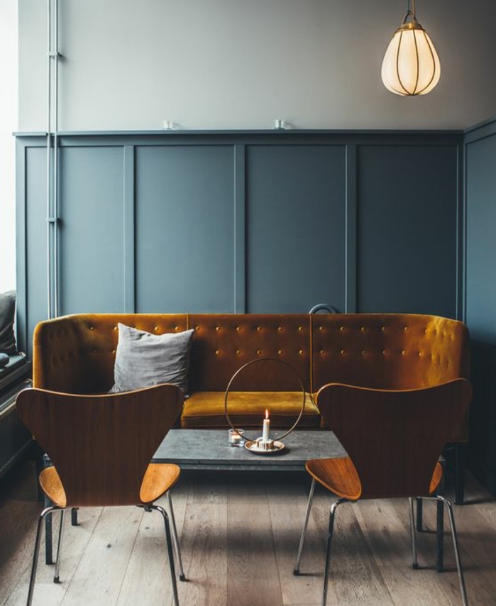 interieur vintage industriel, deco bleu et jaune, canapé jaune moutarde, chaises en bois et métal, table basse, mur couleur bleu gris, parquet en bois brut, suspension industrielle