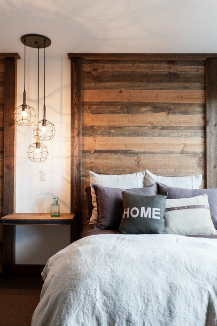 une chambre à coucher rustique moderne à tête de lit en bois, un luminaire suspension à trois lampes