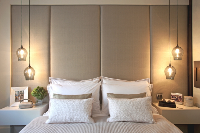 une chambre à coucher aux tons neutres au décor harmonieux, un luminaire suspension bas en verre de chaque côté du lit