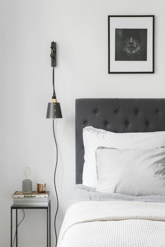 une suspension chevet en laiton noir accrochée au mur, chambre à coucher à intérieur masculin et monochrome