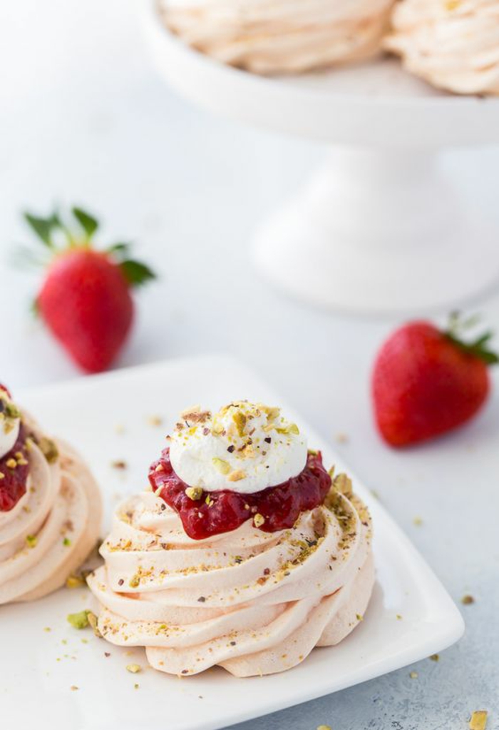 dessert australien meringué, pavlova à l'eau de rose et coulis de fraises saupoudrée de pistaches concassées