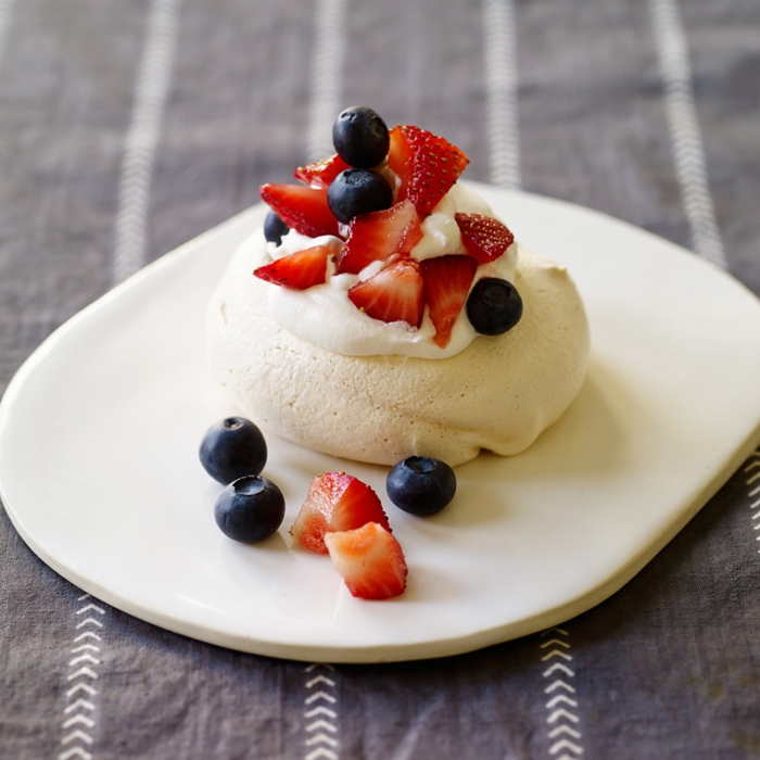 version miniature de la pavlova aux fruits, un base à meringue nappée de crème légère et de fraises