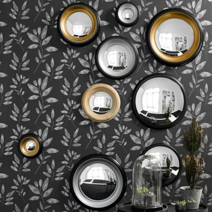 miroir doré sur un mur gris aux feuilles blanches entrée miroirs oeil de sorciere aux tailles diverses