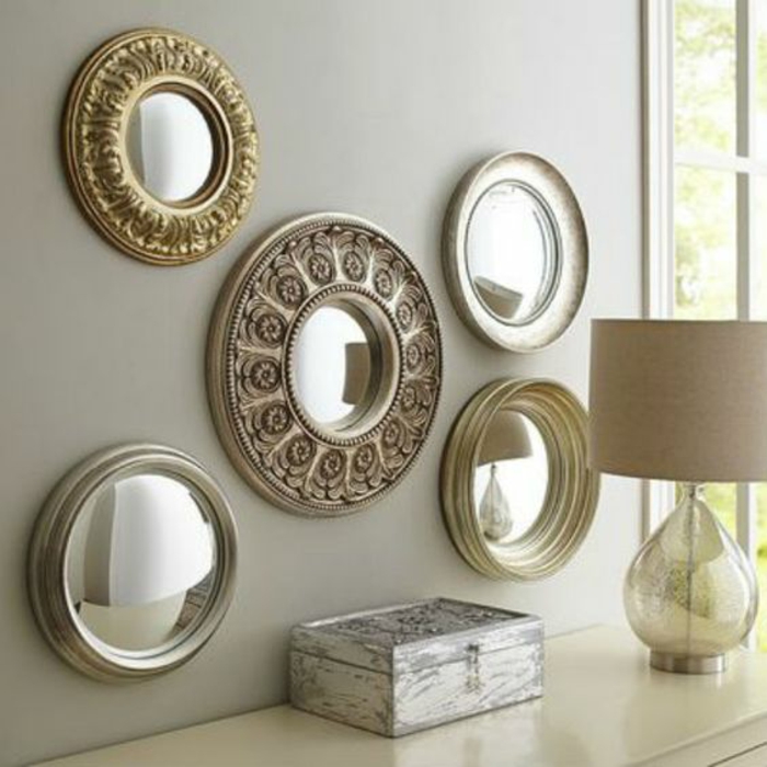 miroir de sorciere 5 de forme ronde sur un mur gris au dessus d'un meuble d'entrée blanc