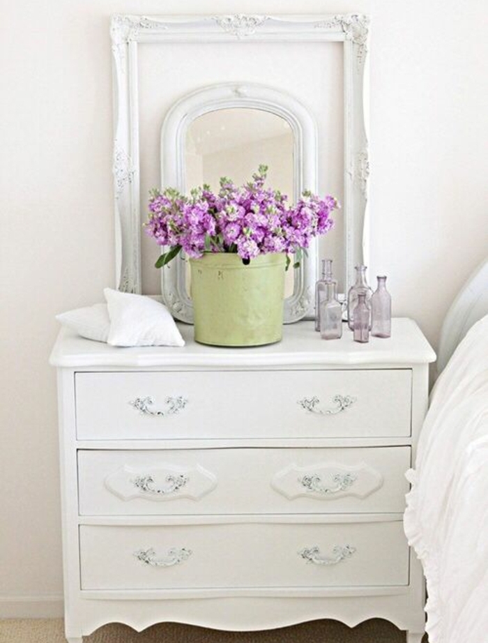 table de nuit blanche avec des tiroirs, seau vert pistache, bouquet de fleurs, deco cadre vide et miroir, linge maison blanc
