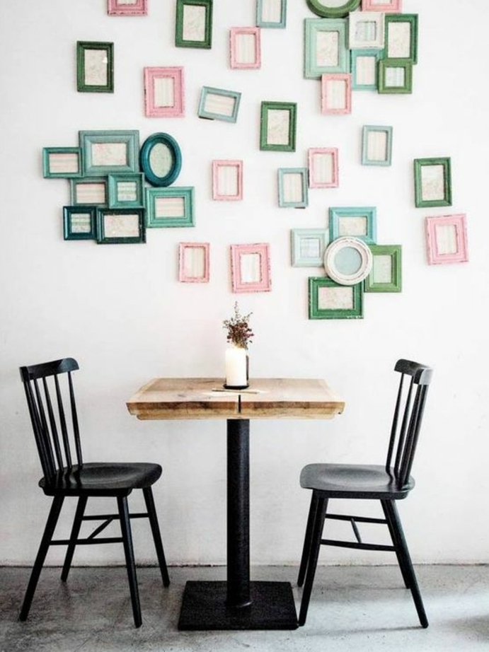 chaises en métal et table en bois et métal, deco cadre vie, mur décoré de plusieurs petits cadres photos verts, bleus et rose, sol en béton ciré