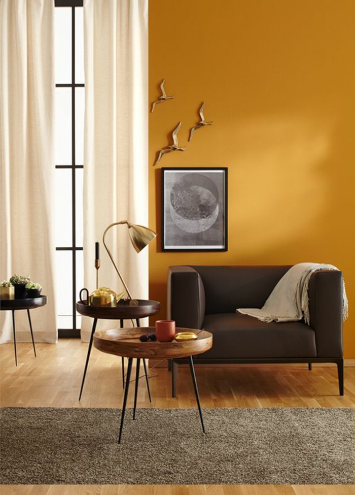 un mur d'accent ocre jaune pour réchauffer l'élégance classique d'un salon, contraste harmonieux entre la peinture ocre et les rideaux blancs