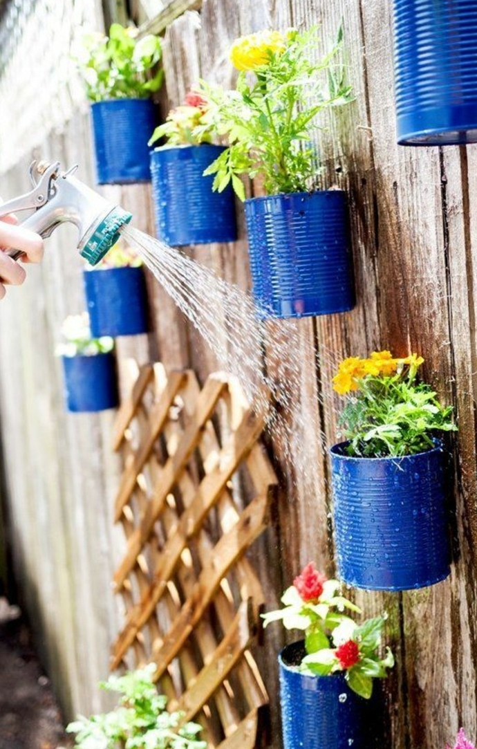 idée de jardinière sur une palissade en bois, deco boite conserve exterieure, grosse boite de conserve repeinte en bleu, diy pot de fleur, fleurs multicolores