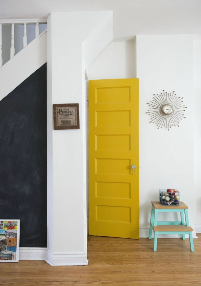 une porte en ocre jaune vive en contraste avec le pan de mur en ardoise