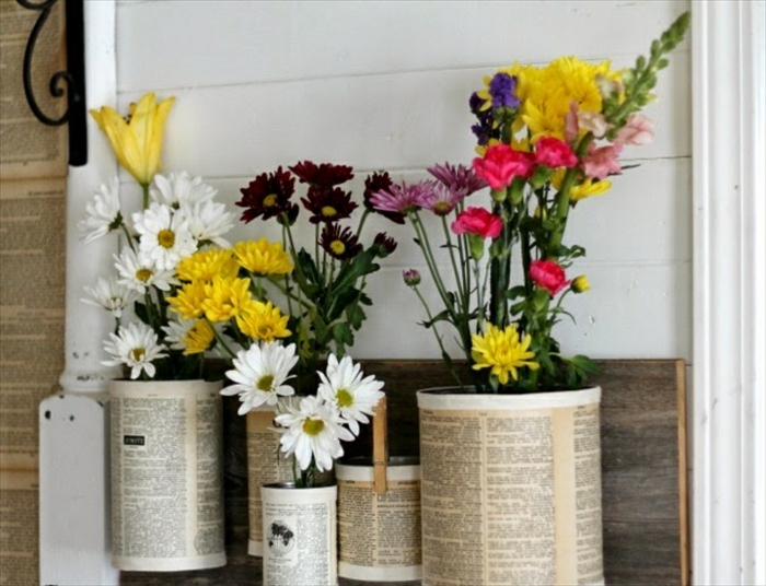 idée de recyclage boite de conserve, une jardinière constituée de boites de conserve attachées sur une planche en bois et customisées de papier journal, des cache pots originaux
