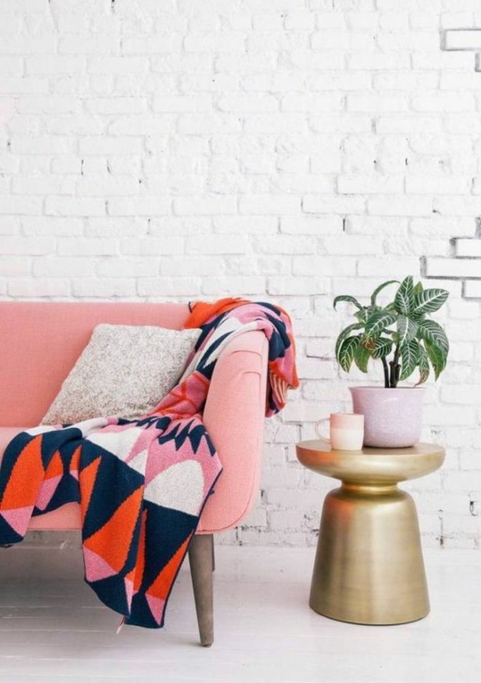 sofa rose corail et plaid de lit en couleurs radiantes, mur en briques blanches
