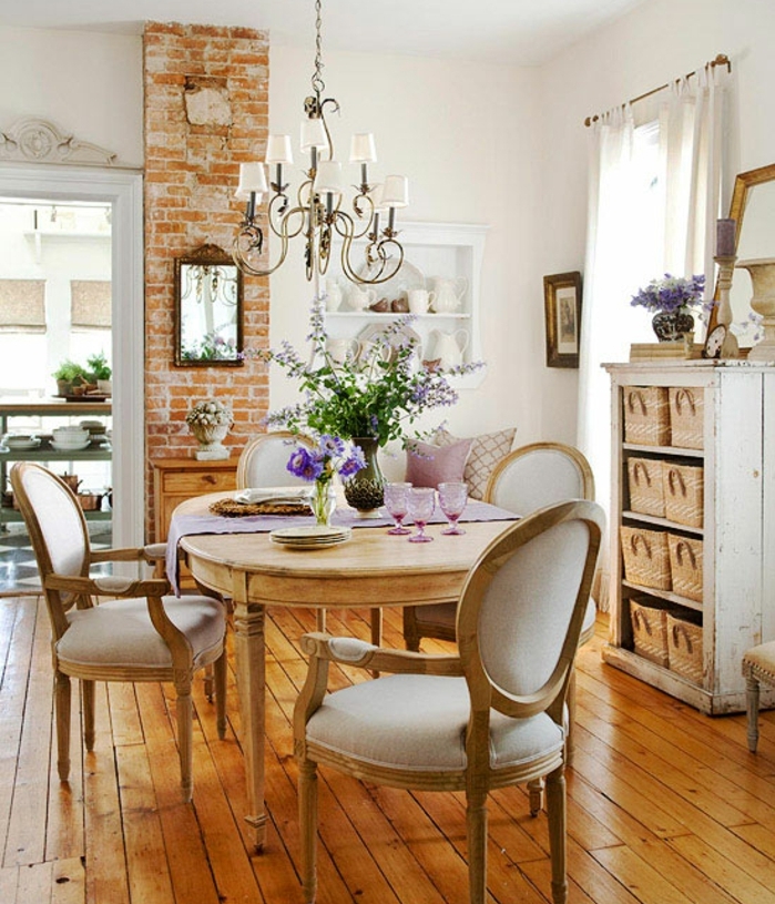 modele salle à manger campagne chic, chaises et table en bois, pan de mur en briques, meuble de rangement avec paniers en rotin, lustre baroque, deco shabby chic