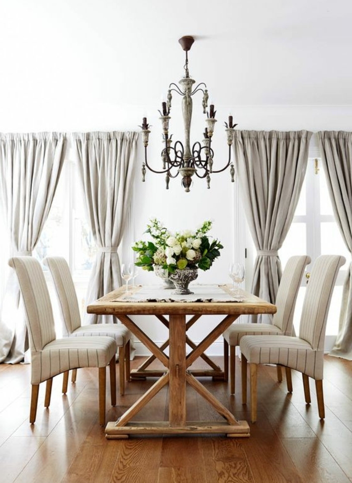 idée comment décorer une salle à manger, parquet clair, table campagne chic, chaises blanches, lustre baroque, rideaux gris, centre de table floral