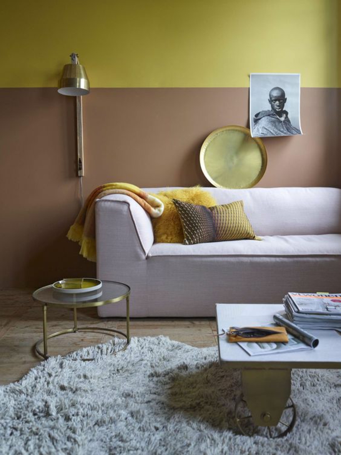 salon d'une ambiance chaleureuse et apaisante, mur bicolore de couleur ocre et d'or aux accent cuivré, canapé moderne rose pastel