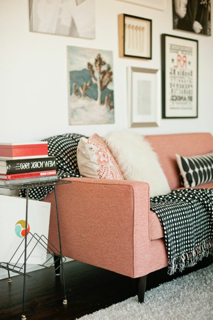 sofa rose saumon, coussins décoratifs, tableaux encadrés, petit chevet avec des livres