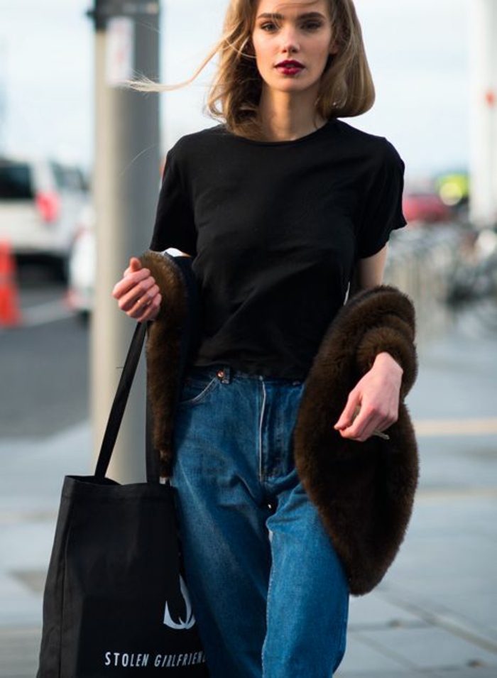mode année 80 jean bleu foncé taille haute avec T shirt noir simple et veste fausse fourrure manches courtes