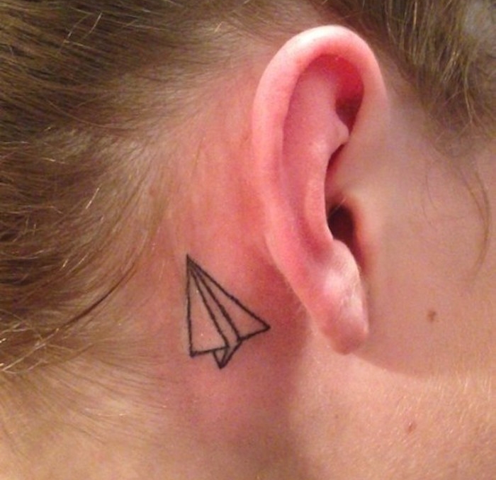 tatouage avion en papier derrière oreille femme minimaliste discret