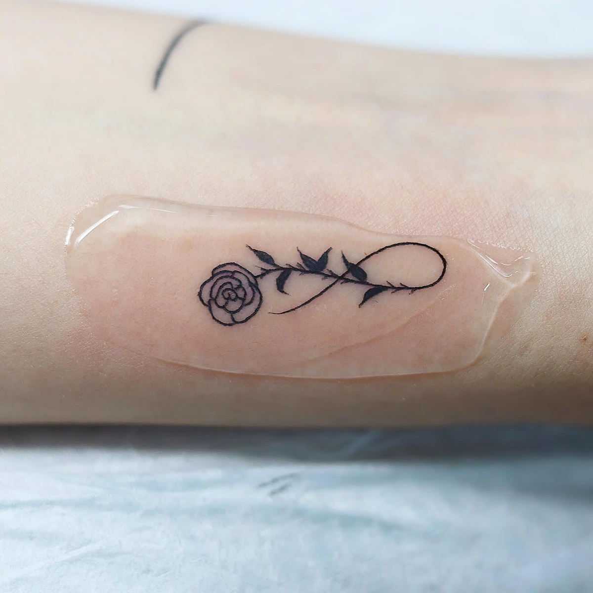 tattoo rose eternel symbole feuilles courbe ligne dessin minimaliste