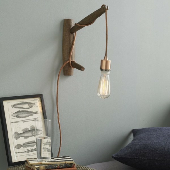 une suspension chevet en cuivre façon baladeuse accrochée à un support en bois, éclairage fonctionnel dans la chambre à coucher