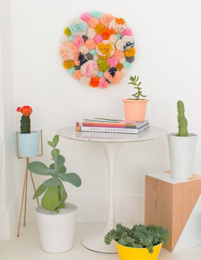 decoration murale, constituée de pompons multicolores, table d appoint blanche, plantes vertes, activité créative
