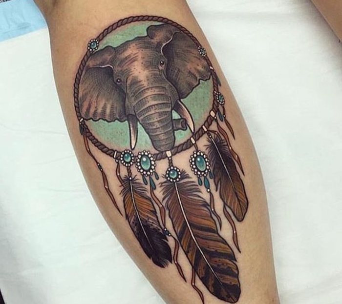 attrape reve tatouage aux plumes noires et marron, perles bleu vert, dessin tête d éléphant sur un fond vert