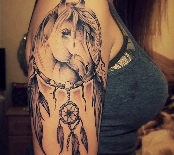 tatouage attrape reve, grand cerceau avec un dessin de cheval à l'intérieur et un petit capteur de reves, plumes graphiques