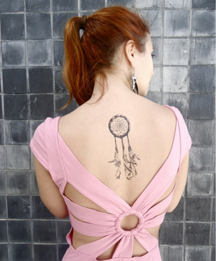 attrape reve tatouage sur le dos, lignes graphiques, cerceau, filet et plumes, robe rose, cheveux roux, boucles d oreilles plumes