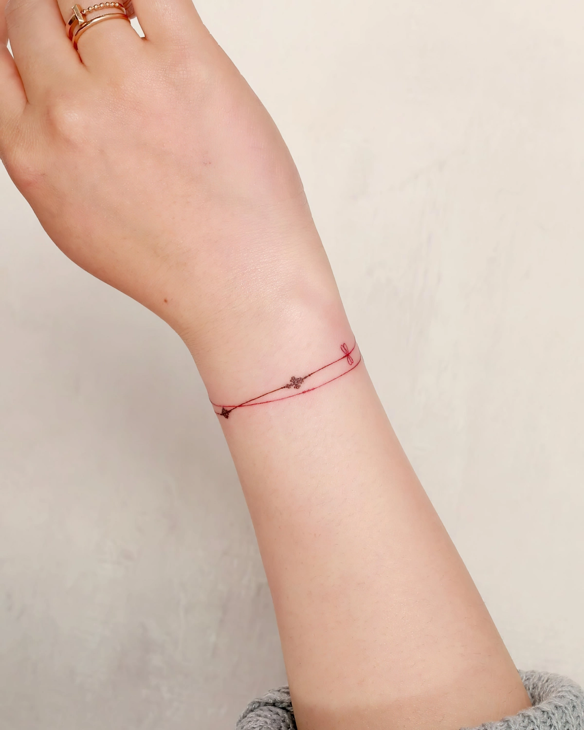 bague or main bras femme dessin en couleur sur peau bracelet ficelle rouge