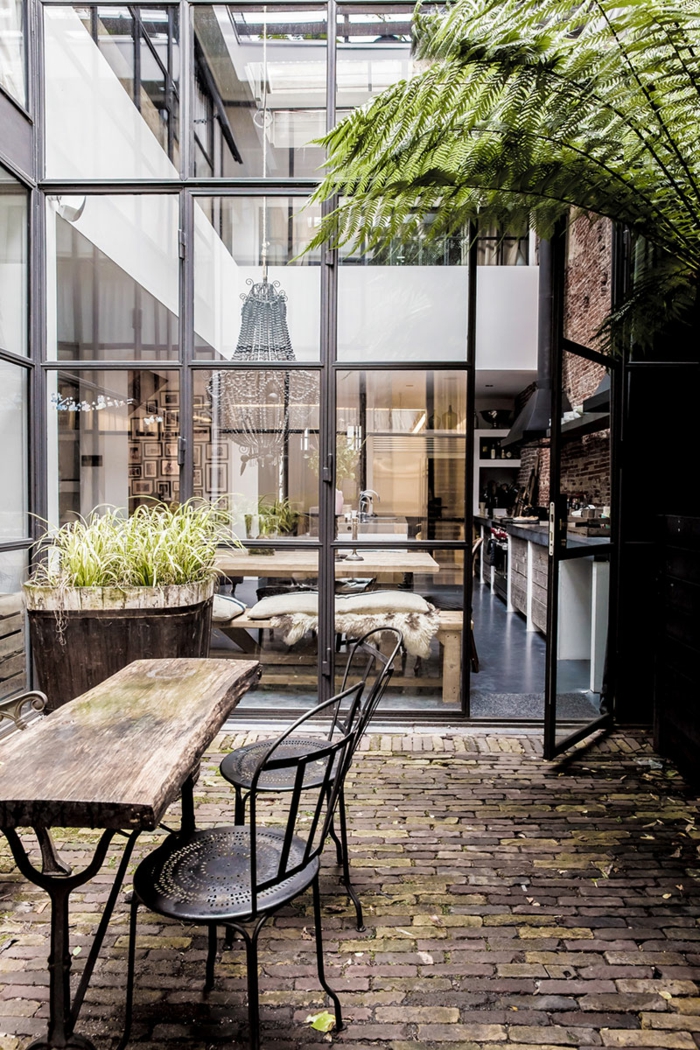 table basse industrielle, décoration extérieur, plante verte, grandes fenêtres, plancher en pierres, idee deco industrielle