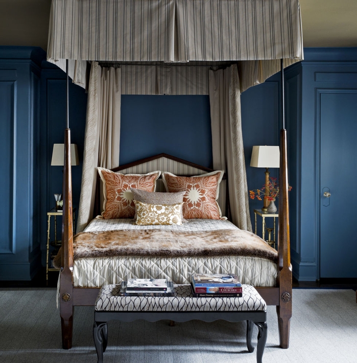 une chambre à coucher de style masculine en bleu marine et vert olive, un lit à baldaquin aux tons neutres, coussins couleur sienne