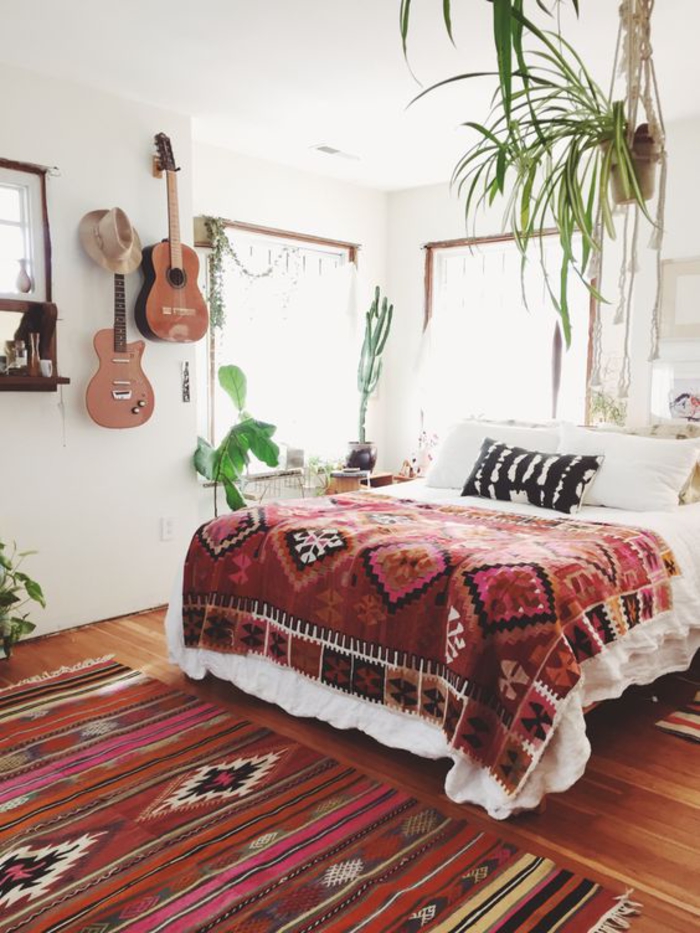 une chambre à coucher bohème chic, un tapis à motif ethnique combiné avec une couverture de mêmes motifs
