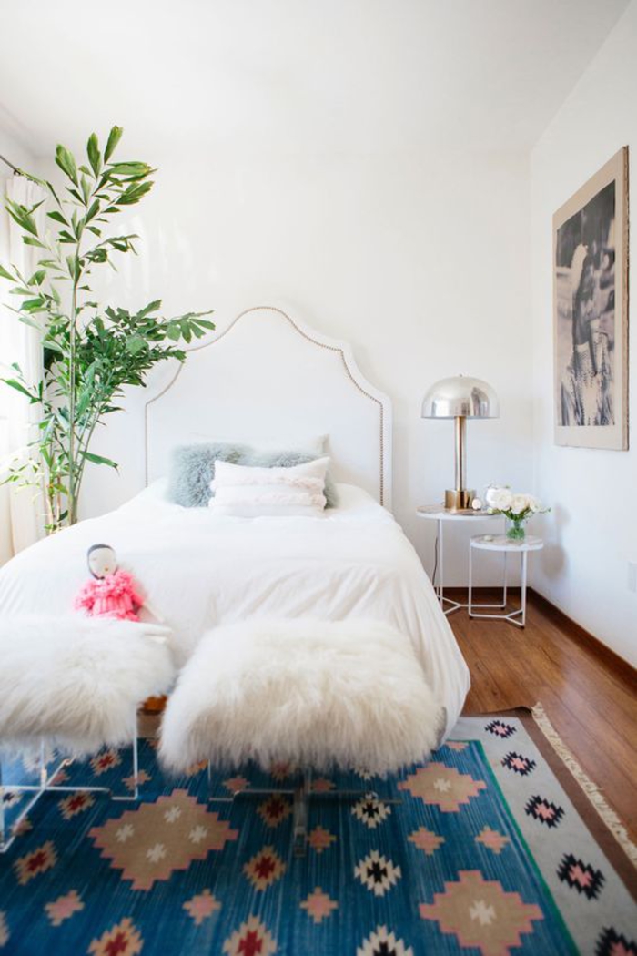 une chambre à coucher élégante en blanc, des tabourets métalliques blancs d'assise en fausse fourrure, tapis ethnique chic bleu