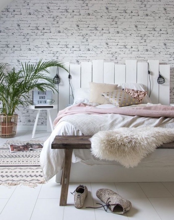 tete de lit en palette démontée, planches de bois repeintes en blanc et linge de lit blanc et rose, coussins multicolores, revetement sol blanc, tapis à motifs géométriques, plantes, lampes