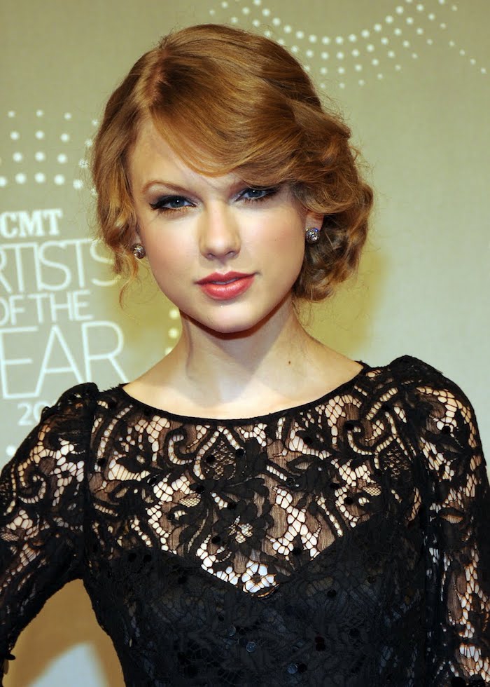 un blond roux sublimé par un chignon bas façon rétro et une robe noire en dentelle
