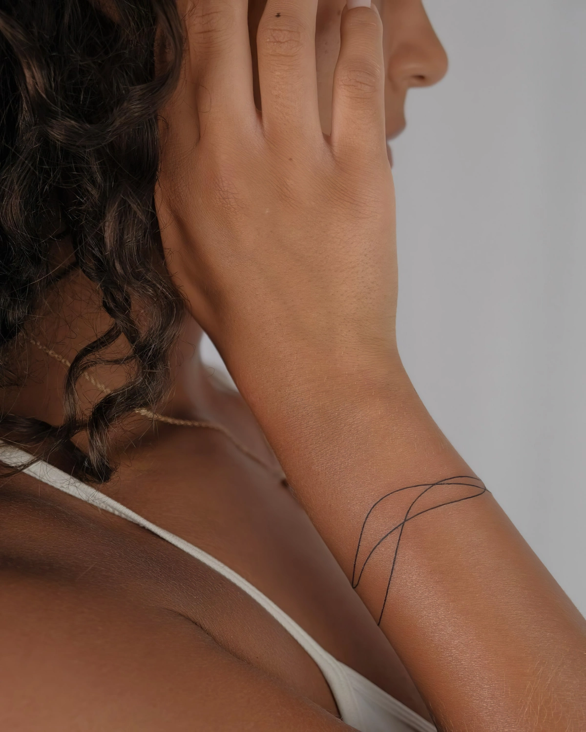cheveux frises tatouage bracelet fin dessin peau minimaliste debardeur blanc