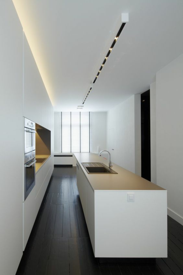 cuisine bois noir pièce en longueur plafond blanc avec des petits luminaires combinés avec lumière jaune incorporée au plafond