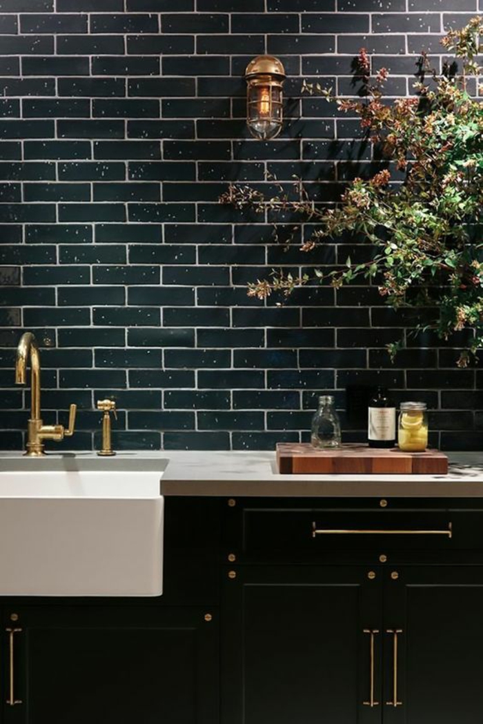 deco cuisine noire avec mur revetu en briques noires polies vasque lavabo blanc évier en métal jaune effet doré 