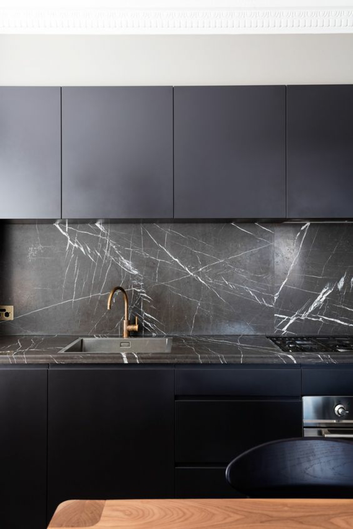 cuisine noir et bois avec mur au dessus du lavabo en matière imitation marbre noir 