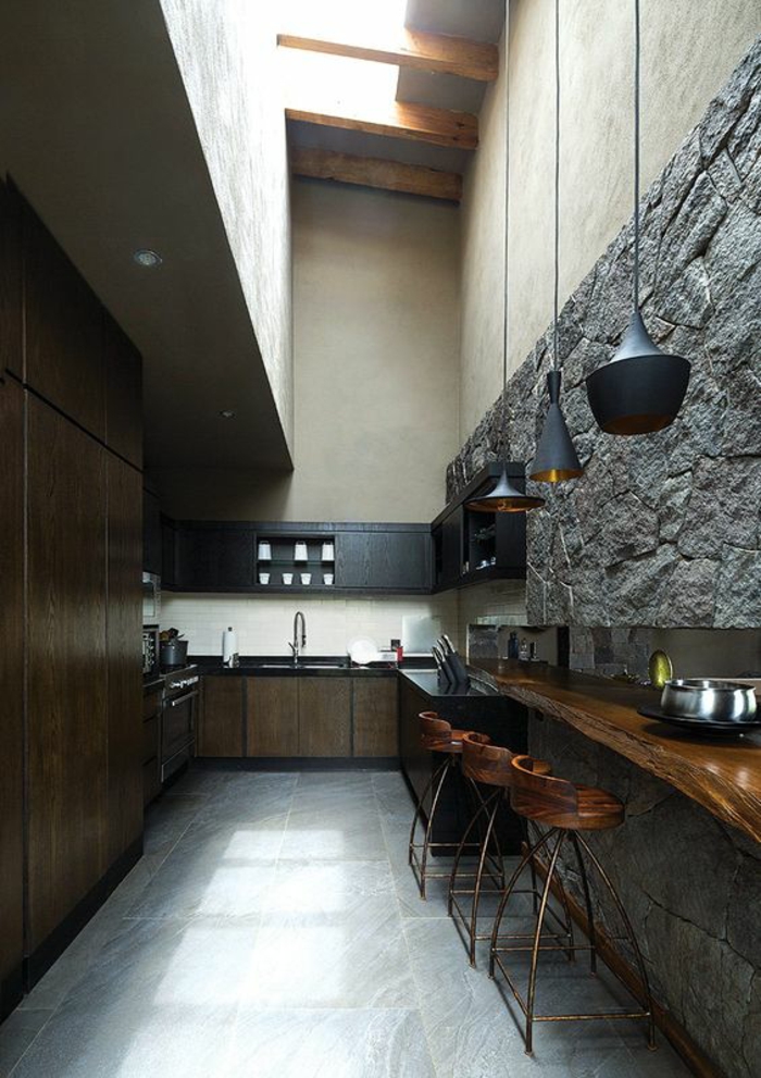 cuisine noir dans un style rustique avec des pierres grises comme revetement sur l un des murs 