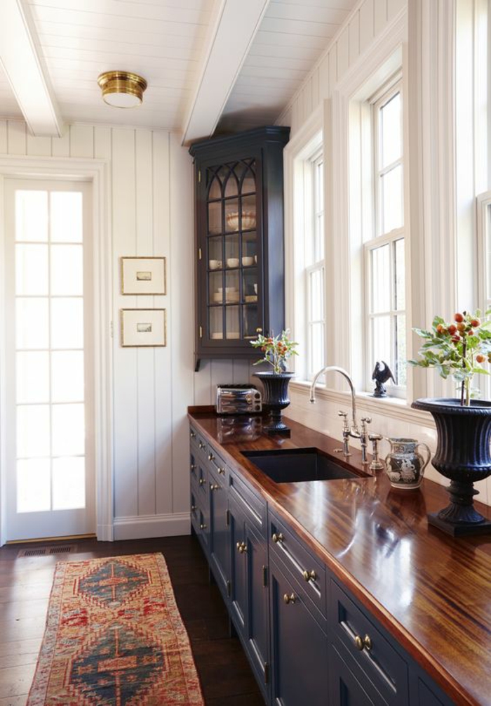 cuisine en noir avec murs et plafond blanc et meuble angulaire pour ranger avec vitrine de style gothique 