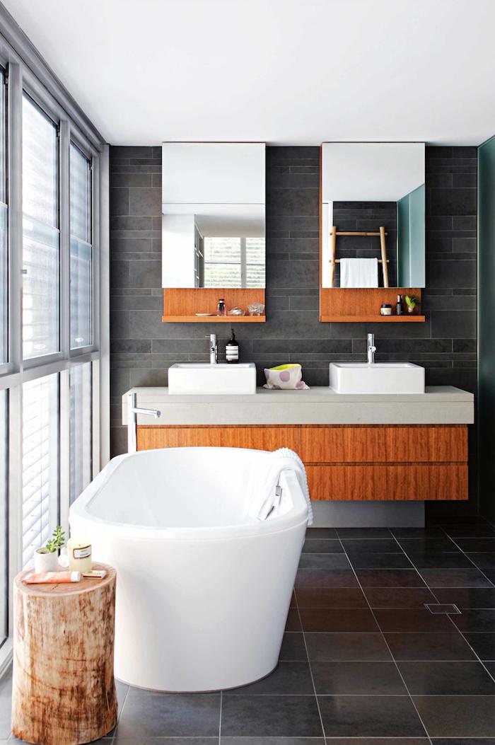 meubles salle de bain, dallage gris, baignoire céramique, petite table en bûche de bois, stores blancs