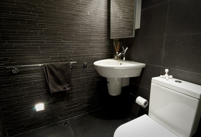 salle de bain design, serviette noire, mur gris foncé, robinet en acier, cuvette wc blanche 